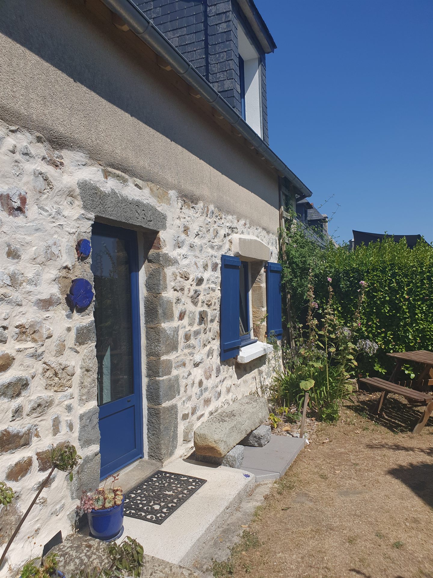 Steinfassade von Ty Ar Mor mit blauen Fensterläden, ein Fischerhaus von 1864 in Kersiguenou