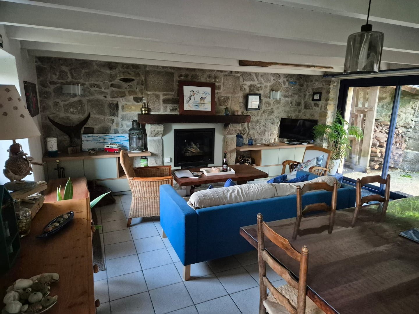 Wohnzimmer von Ty Ar Mor mit Kamin, Natursteinwand und blauem Sofa, in Kersiguenou